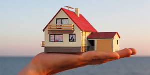 model of house with garage on hand against sea