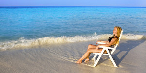 Young pretty woman tans in beach chair  in ocean