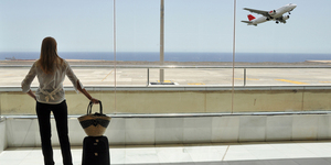 Girl at the airport window looking to the ocean