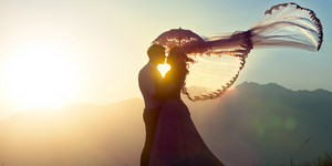 The groom and the bride kiss in mountains against a decline.